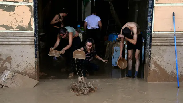 People work to push flood water out of a residential building in Valencia