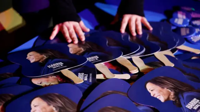 A person touches a table with signs with Harris' face on them at her Nevada rally.