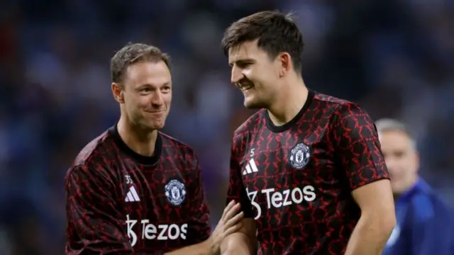 Jonny Evans and Harry Maguire smile while warming up together during Manchester United's draw in Porto