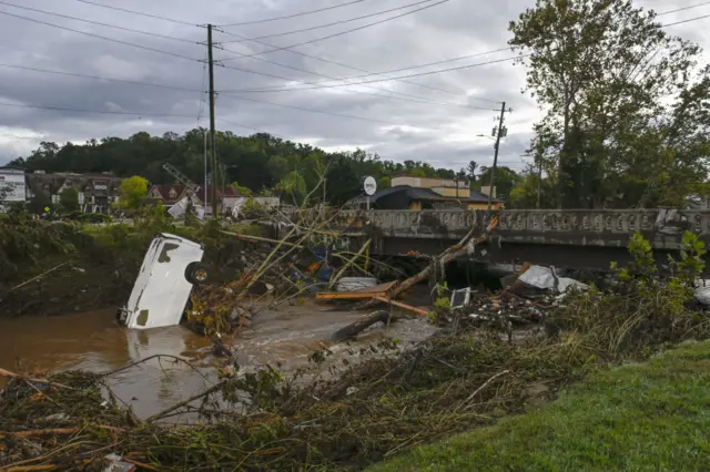 A river filled with debris and an upside down car in North Carolina