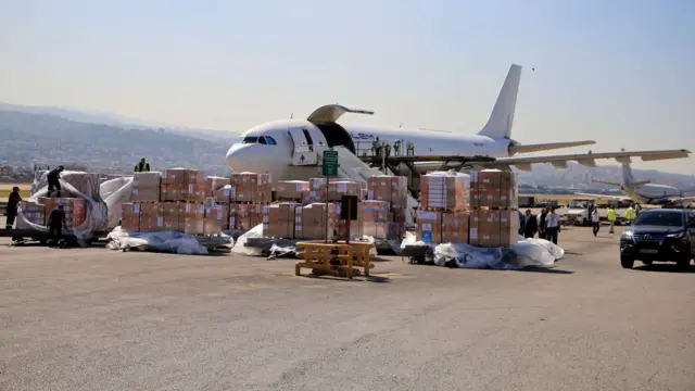 Pallets with boxes on the runway as a plane is being unloaded