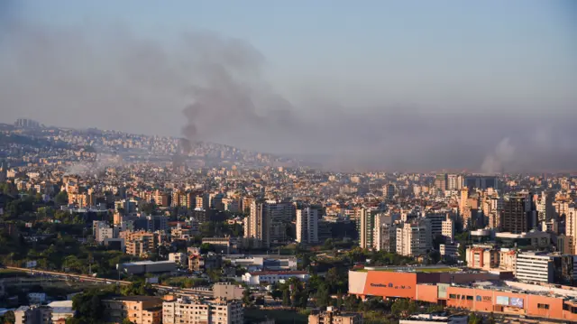 Smoke billowing up out of the city in multiple places across a cityscape of Beirut