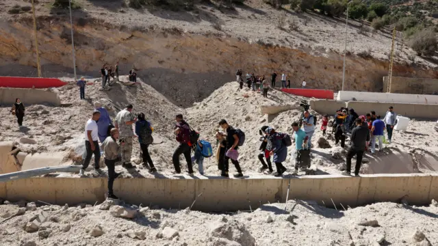 People walking across a beam through a hole in the ground