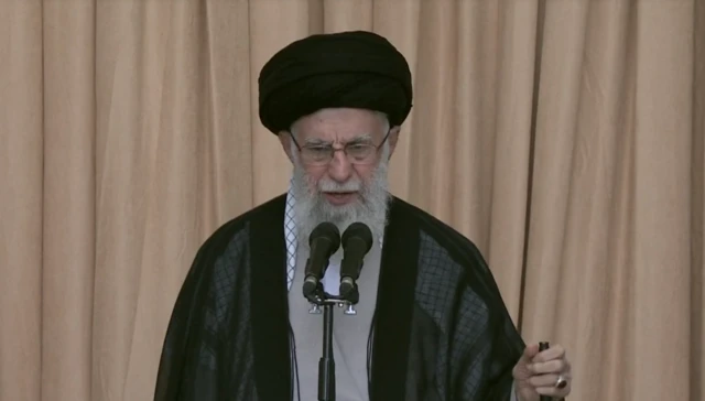 Headshot of Ayatollah Ali Khamenei speaking in front of two microphones