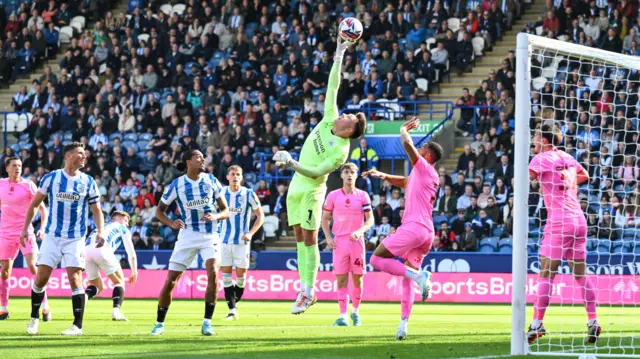 Barnsley goalkeeper Gabriel Slonina stretches to save from Huddersfield's Bojan Radulovic