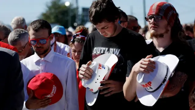 Attendees participate in the pledge of allegiance during the pre-program at a campaign rally for