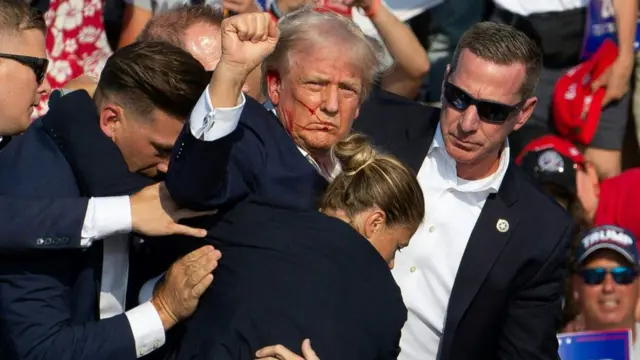 Republican candidate Donald Trump is seen with blood on his face surrounded by secret service agents as he is taken off the stage at a campaign event at Butler Farm Show Inc. in Butler, Pennsylvania, July 13, 2024