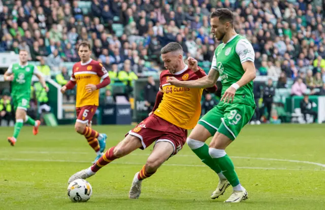 Motherwell's Paul McGinn clears under pressure from Hibernian's Mykola Kukharevych