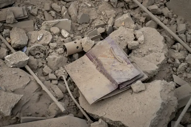 The remains of purple bags from a sweet shop are seen in the rubble of an air strike