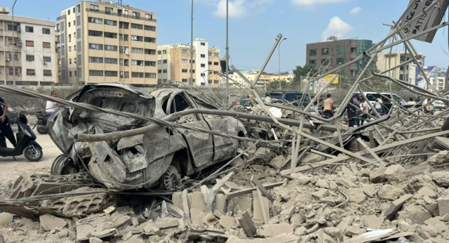 A damaged car lies next to some rubble and broken metal following an Israeli air strike in Beirut