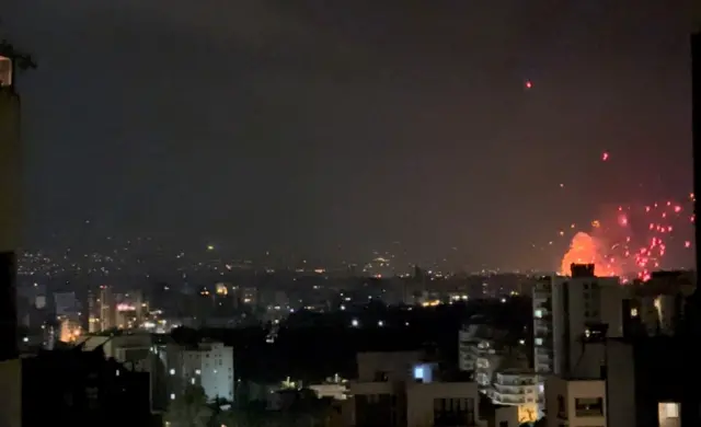 An explosion can be seen dominating the Beirut night sky - orange particles like fireworks fill the sky