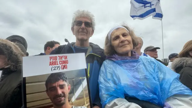 Harold Rosenberg and his wife pose with a picture of a hostage being held in Gaza by Hamas