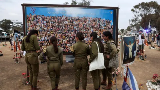 Five women look at a billboard featuring images of individuals