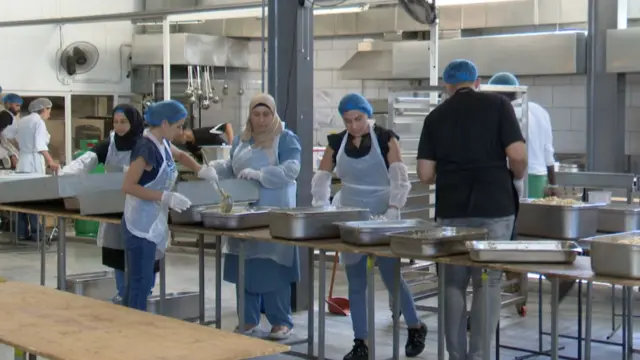 Staff and volunteers at a food kitchen prepare food in batch for displaced Lebanese people