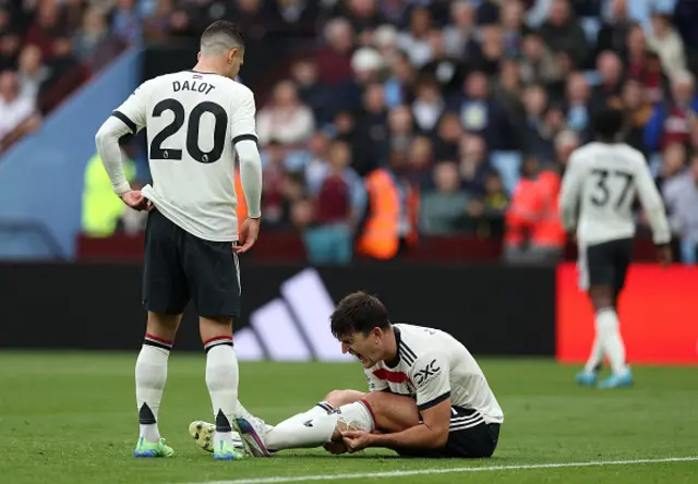 Harry Maguire holds his calf as he sits on the pitch