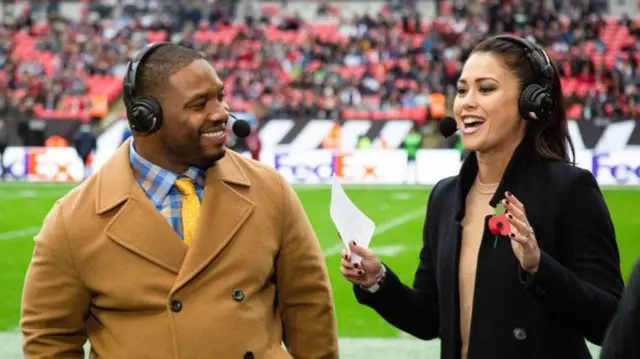 Maurice Jones-Drew speaking to Sam Quek on the sideline at an NFL game at Wembley in 2019