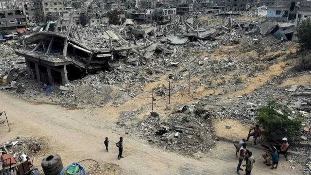 Palestinians walk past the rubble of houses destroyed in Israel's military offensive, amid the ongoing conflict between Israel and Hamas, in Khan Younis