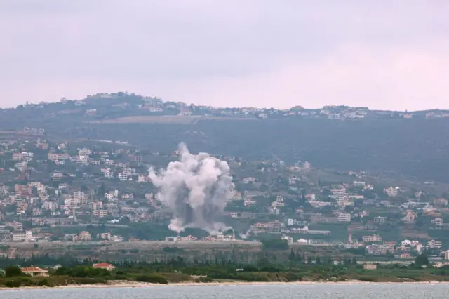 Wide shot showing the coastline of Tyre, southern Lebanon, with plumes of smoke rising from built up areas