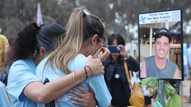 A woman hugs another woman crying