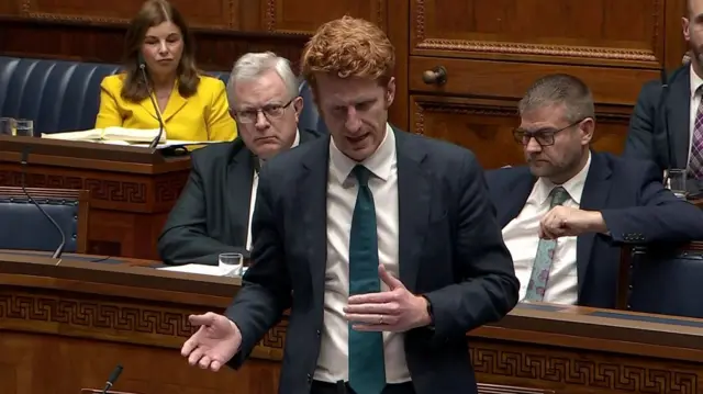 A man in a black suit and a green tie