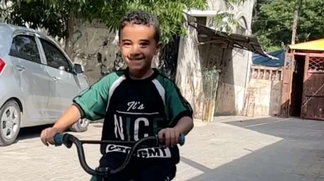 A boy in a T-shirt riding a bike