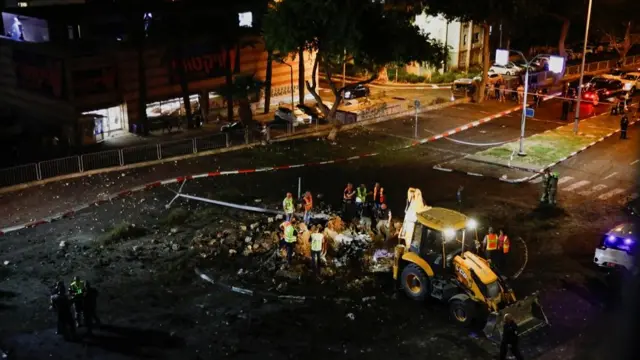 Members of the Israeli rescue forces inspect the site where a projectile struck