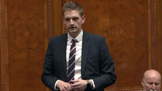 Man in a black suit and red white and black striped tie