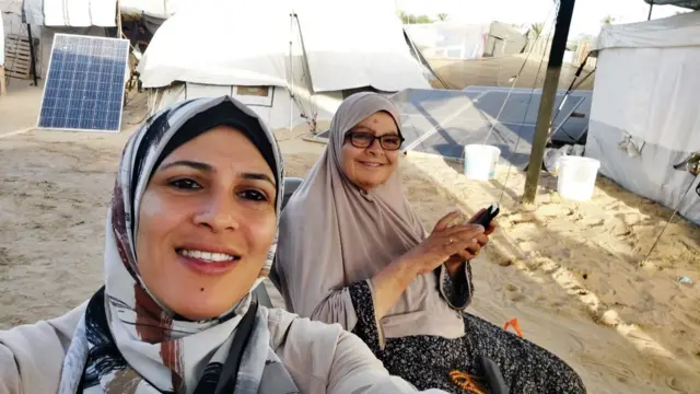 Nashwa and a relative sit outside a tent