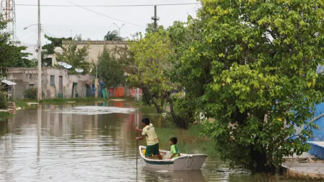 Children navigate a boat in floodwaters after Hurricane Milton brought heavy rain to Mexico's Yucatan Peninsula on its way to Florida, in Celestun, Mexico October 8, 2024.