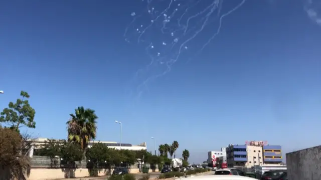 Projectiles are intercepted in a blue sky over Haifa.