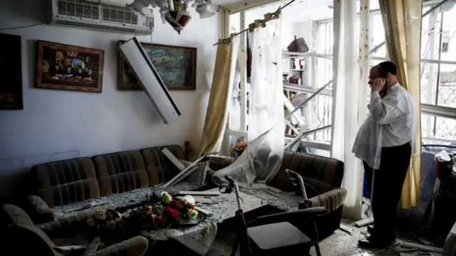 A man stands inside an apartment building damaged by a rocket fired from Lebanon in Kiryat Yam, near Haifa, earlier today