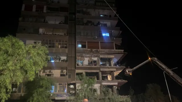 Rescuers work at the site of an Israeli airstrike that targeted a residential building in the Mezzah suburb west of the capital of Damascus