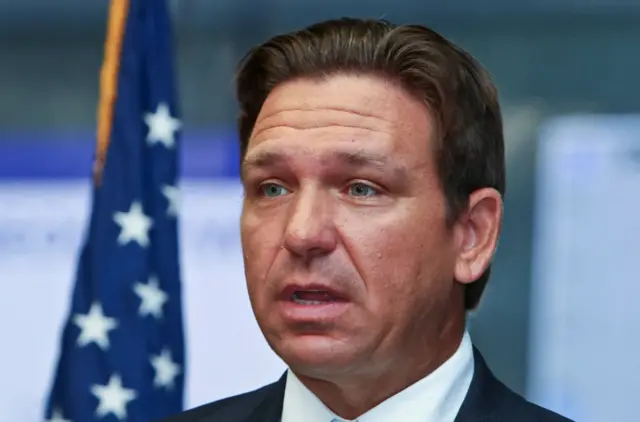 Close up of Ron DeSantis, US flag behind him to his right