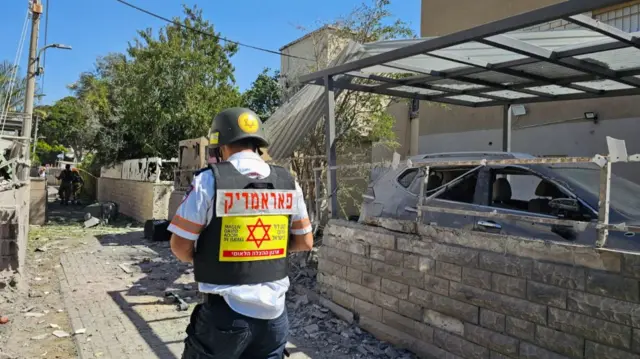 A man in an MDA emergency service vest standing on a street.