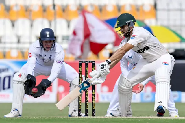 Pakistan's Agha Salman (R) plays a shot as England's wicketkeeper Jamie Smith watches during the second day of the first Test cricket match between Pakistan and England at the Multan Cricket Stadium