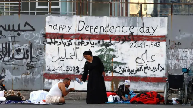 A woman pours water from a plastic bottle into the hands of a man in Martyrs' Square