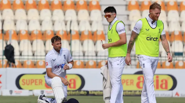 England's Joe Root has a drink after a muscle cramp as Matthew Potts and Ben Stokes look on