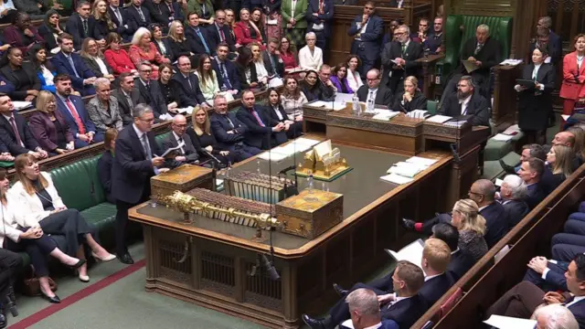 Starmer standing up speaking at Prime Minister's questions. Both front benches can be seen listening