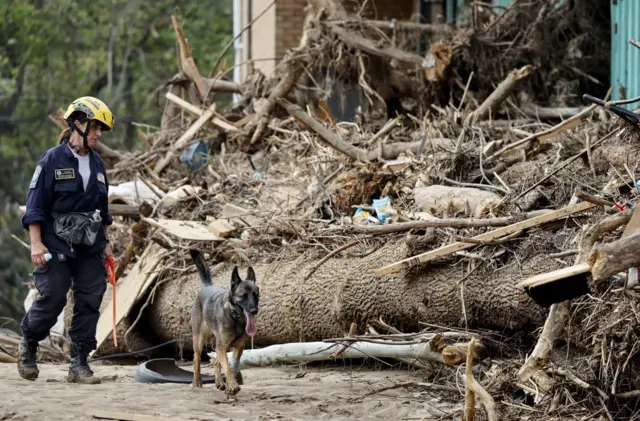 A member of the FEMA Urban Search and Rescue Task Force searches a flood-damaged property with a search canine in the aftermath of Hurricane Helene