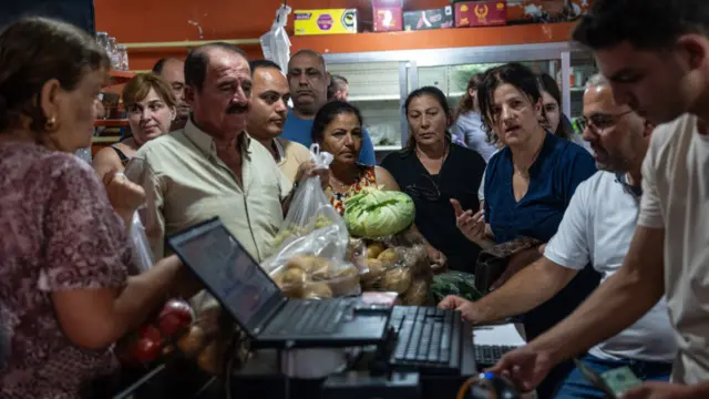 People rush to buy food after a convoy delivered goods to the town of Rmaich in southern Lebanon