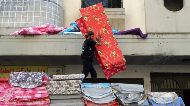 Workers distribute mattresses to displaced people in Tripoli, in Lebanon's north