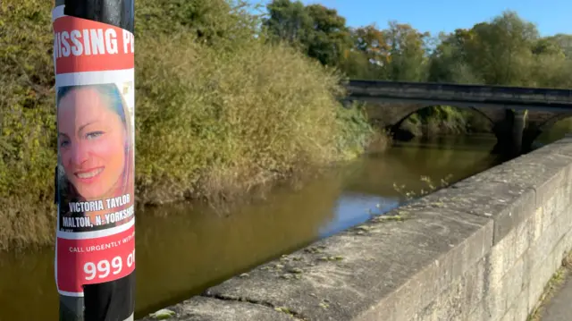 A poster appealing for information regarding missing woman Victoria Taylor on a post next to the River Derwent in Malton.