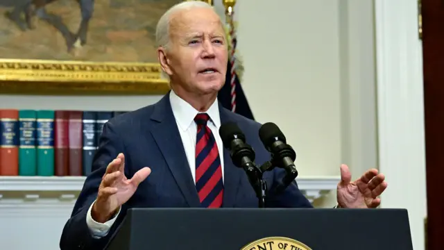 Biden stands behind a lectern and makes gestures with his hands