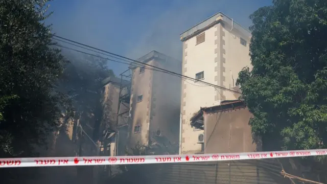 Smoke rises from a residence damaged during a rocket strike by Hezbollah in Kiryat Shmona