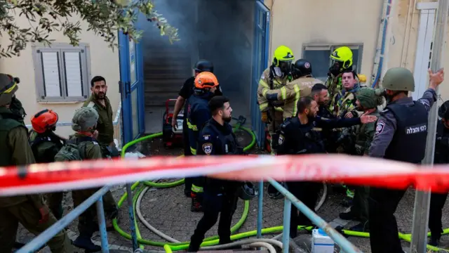 Firefighters gather in front of a residence damaged by rockets fired by Hezbollah in north-east Israel.