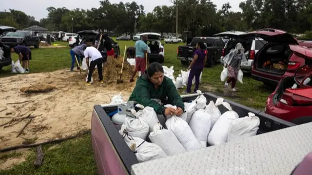 A woman places bags filled with sand in the back of a vehicle in preparation for Hurricane Milton in Orlando, Florida.