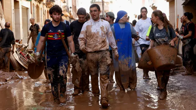 Parish priest of Paiporta walks on a street covered in mud in the aftermath of torrential rains that caused flooding, in Paiporta