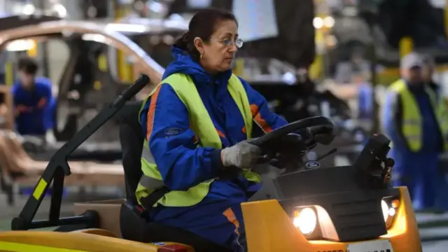 A female warehouse worker driving a factory-floor vehicle