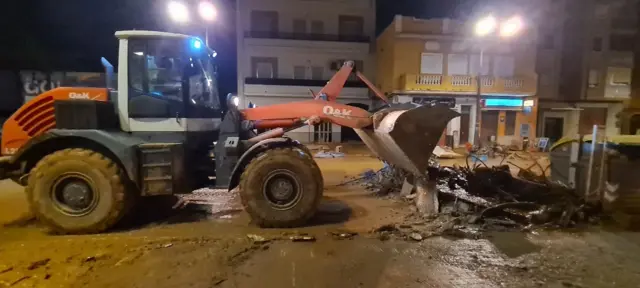 A digger cleans up rubble on muddy streets in the La Torre area of Valencia