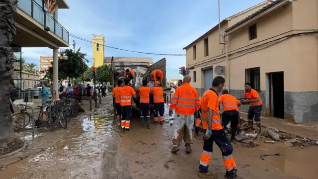 Council workers clean up a muddy street in Valencia